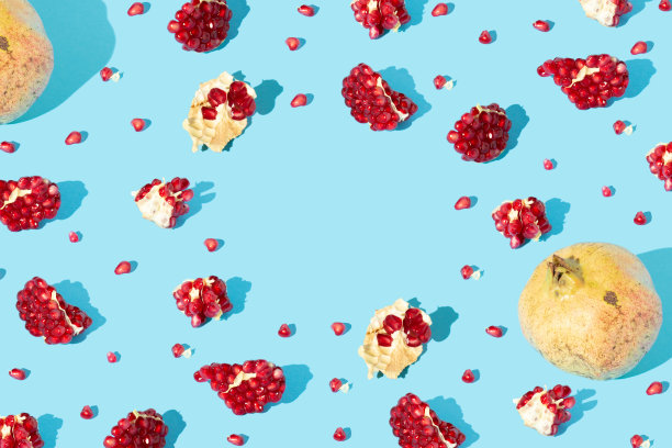 红色的石榴片和种子孤立在蓝色背景。秋果或自然概念。最小的风格。副本的空间。图片下载