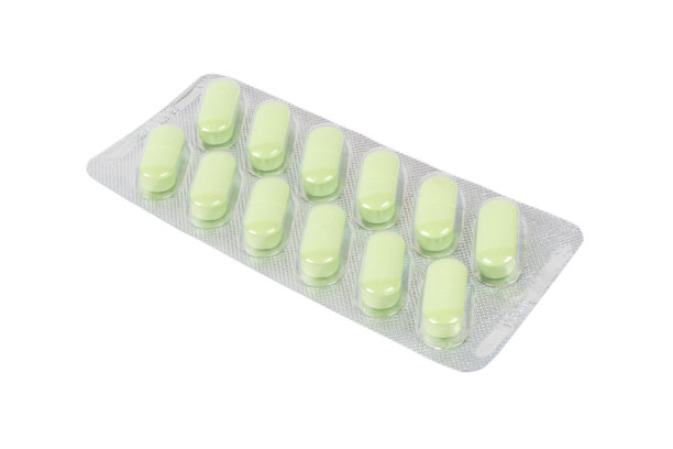 微距镜头堆绿色药片在水泡包装隔离在白色背景。铝箔吸塑包装。药丸和药品接近。卫生保健。片的背景图片下载