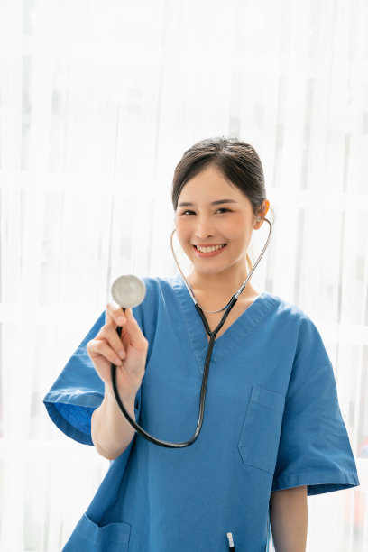 医护人员的医学观念，表情自信的专业女医生，穿着蓝色医疗服，拿着听诊器微笑的亚洲女医生图片下载