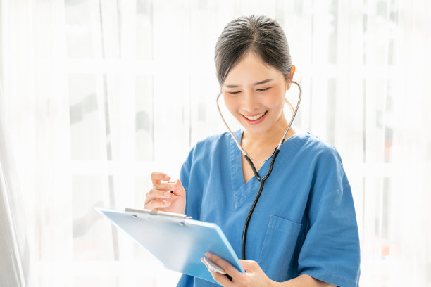 医学概念自信的女医生穿着蓝色的医疗服，拿着听诊器站在那里，拿着文件夹，亚洲妇女在医院工作，看着报告单，微笑着图片下载