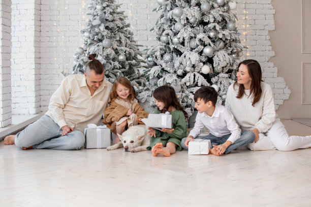 家庭——爸爸、妈妈、三个孩子和一条狗，在家里一棵装饰好的圣诞树下快乐地庆祝圣诞节图片下载