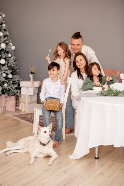 家庭——爸爸，妈妈，三个孩子和一条狗，快乐地一起在家里的桌子上装饰圣诞树庆祝圣诞节图片下载
