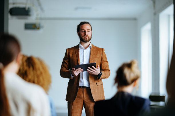 一名严肃的商人手持平板电脑在演讲中与观众交谈图片下载