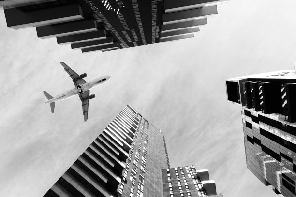 飞机飞过摩天大楼。图片下载