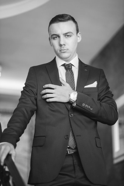 一个穿着蓝色西装的自信白人青年靠在楼梯栏杆上的灰度图图片下载