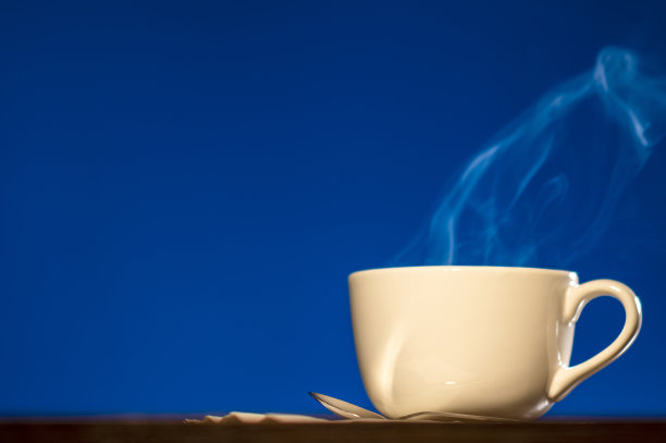 在蓝色背景下，一大杯咖啡或茶中冒出的蒸汽图片下载