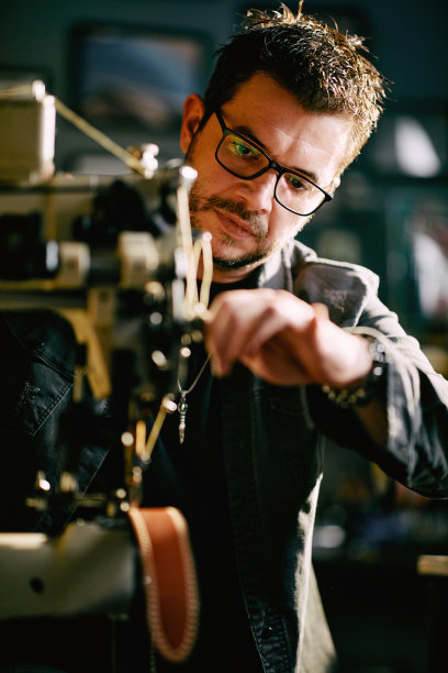 一个年轻人在他的工作室缝皮带图片下载