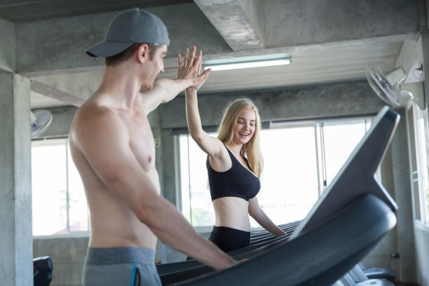 年轻男女在体育馆里的跑步机上跑步。一群运动员在体育馆里用跑步机锻炼图片下载