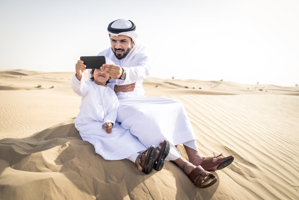 阿拉伯男子和儿子在沙漠中玩耍图片下载