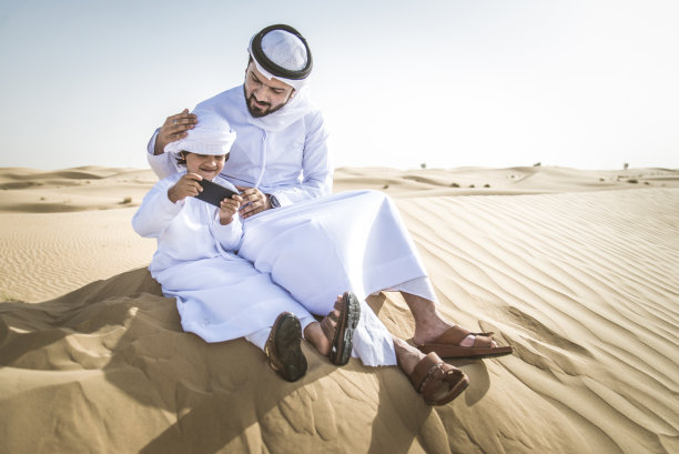 阿拉伯男子和儿子在沙漠中玩耍图片下载