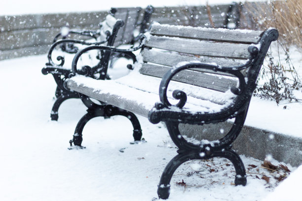 大雪期间，公园里一张被雪覆盖的木凳的特写图片下载