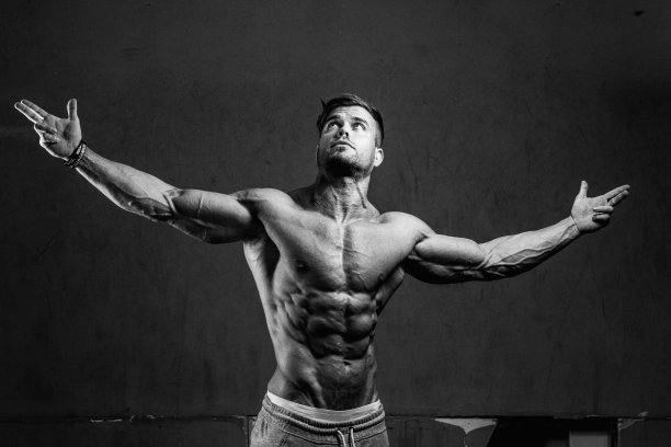 一个英俊的运动肌肉奥地利人在一个黑暗的健身房摆姿势的灰度镜头图片下载