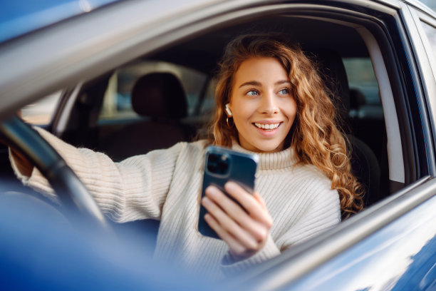 一名年轻女子一边开车一边用智能手机发短信。图片下载