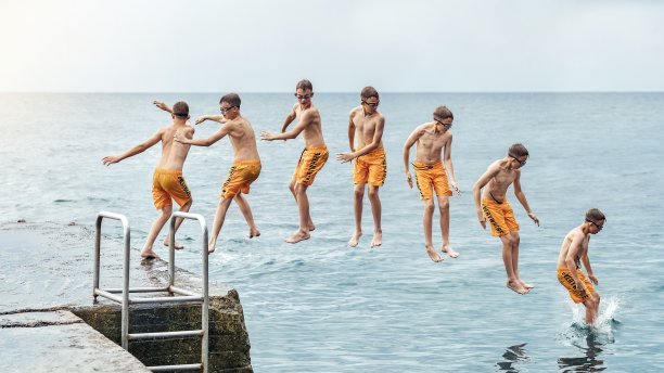 跳跃顺序。学生从码头跳进海里表演杂技的时刻图片下载