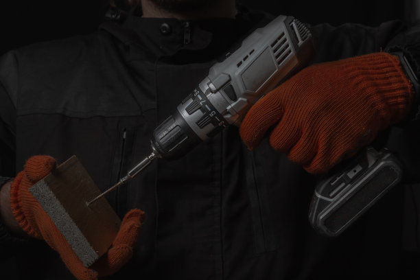 手持无绳电动螺丝刀与钻头螺钉和钻孔隔离在黑色背景图片下载