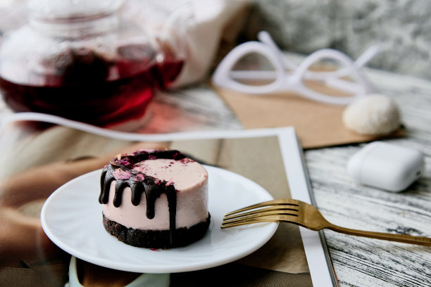 粉色面筋和无糖审美腰果覆盆子蛋糕杂志和茶壶。健康的素食甜点。图片下载