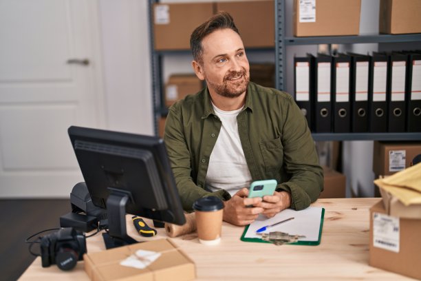 年轻的白人男性电子商务工作人员在办公室使用电脑和智能手机图片下载