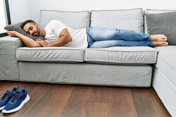 年轻的西班牙人躺在沙发上睡觉在家里图片下载