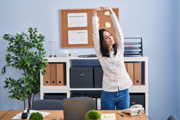 年轻的白人女性商务工作者在办公室伸展手臂图片下载