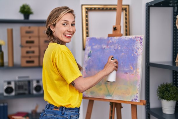 年轻的金发女艺术家微笑自信使用涂鸦喷绘在艺术工作室图片下载