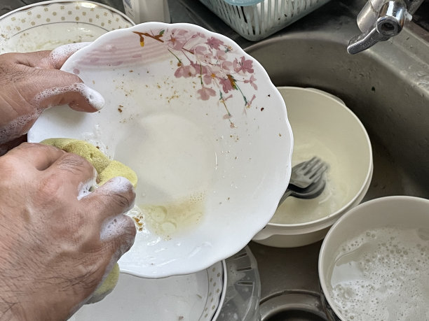 男子用清洁剂清洗盘子图片下载