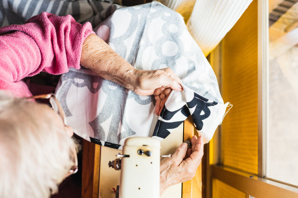 天顶的观点，无法辨认的老年妇女在家里用机器缝制一些织物图片下载