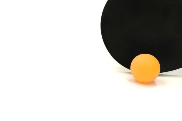 这张图片展示了一个黑面乒乓球拍和一个白色背景的橙色乒乓球。图片下载