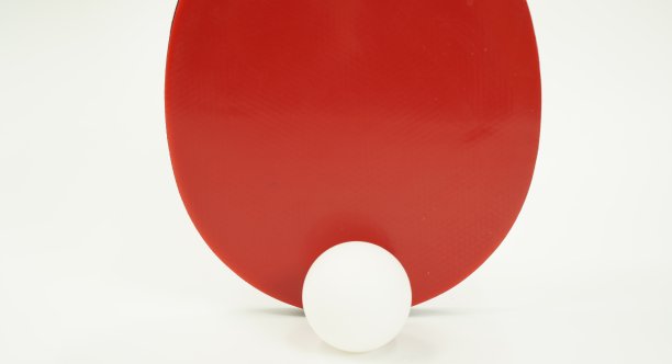 图中是一个红色的乒乓球拍和一个白色背景的白色乒乓球。图片下载