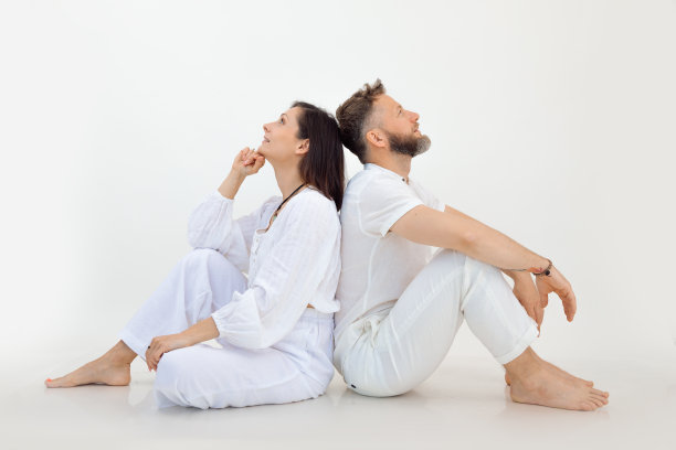 幸福的运动家庭，年轻的女人和中年男人，背靠背坐在地板上，仰望白色的背景。图片下载