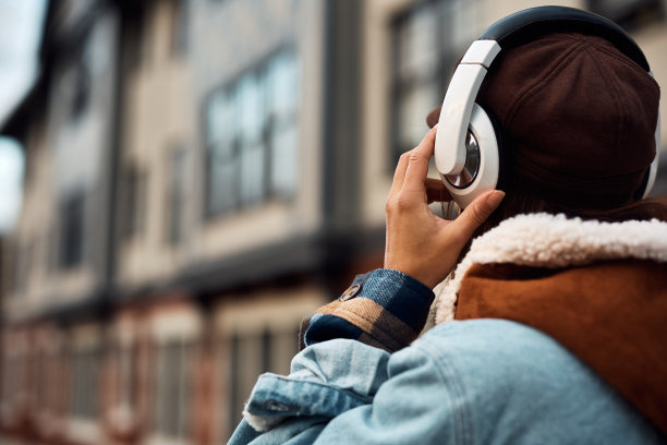 一个戴着耳机走在街上的女人的特写。图片下载