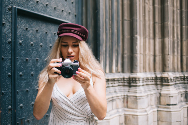 时髦的白人女记者测试在独自旅行旅行中编辑图像的复古相机，时髦的女游客在时髦的红葡萄酒帽子检查老式设备与照片图片图片下载