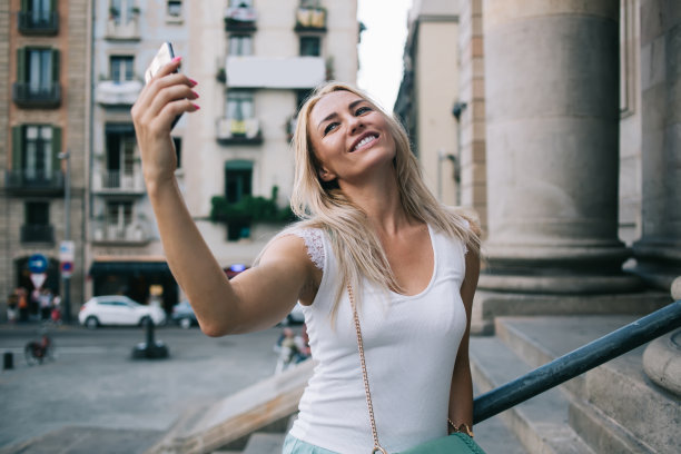 快乐的白人妇女使用前置智能手机摄像头拍摄关于旅行假期的视频博客，快乐的千禧一代游客使用移动设备上的滤镜应用程序制作自拍照图片下载