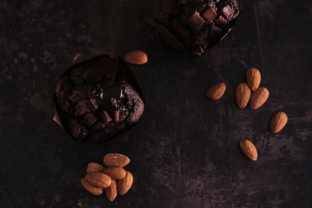 平躺特写的巧克力松饼和杏仁坚果在一个黑色的背景图片下载