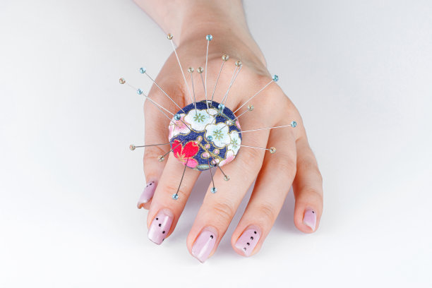 一枚戒指，在白色背景的手上有一个供针用的小枕头图片下载