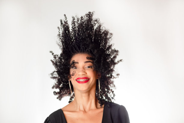 年轻微笑的女人把头发甩到空中。图片下载