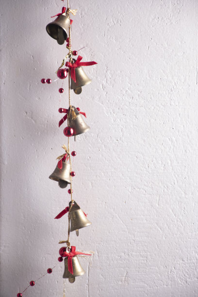 圣诞装饰的金色金属钟与红色闪烁圣诞小玩意特写白色垃圾质感的墙图片下载