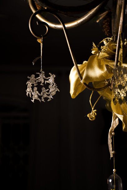 圣诞装饰品铃铛和金色的圣诞场景挂在黑暗的背景在家里弓圣诞贺卡的背景图片下载