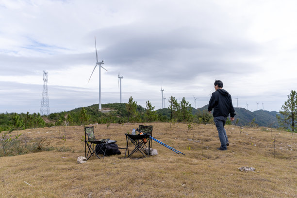 一名中年男子绕着户外营地简陋的桌椅走来走去图片下载