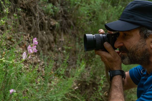 戴着大胡子和帽子的男人正在给一朵花拍照图片下载