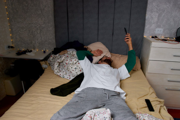 疲惫的男人躺在卧室的床上睡着了，衣服散落在地上图片下载