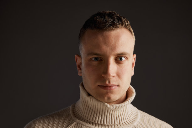 肖像英俊的男子摆着时尚的毛衣孤立在深灰色的工作室背景。时尚和生活方式的概念图片下载