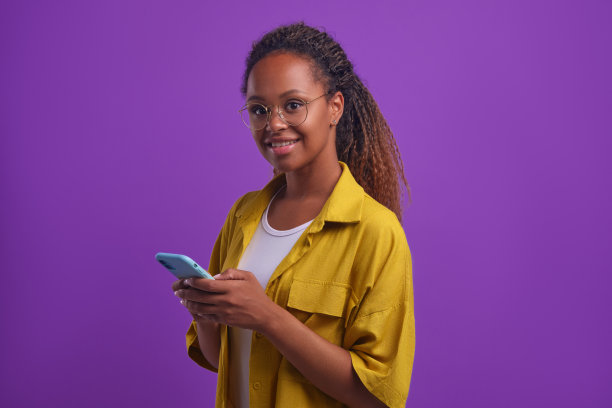 年轻微笑的非洲裔美国女性，长发，手持手机图片下载