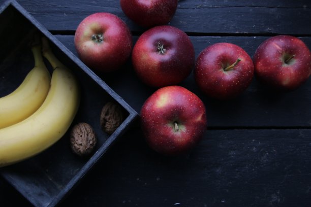 老旧的桌子上放着熟香蕉和苹果。图片下载