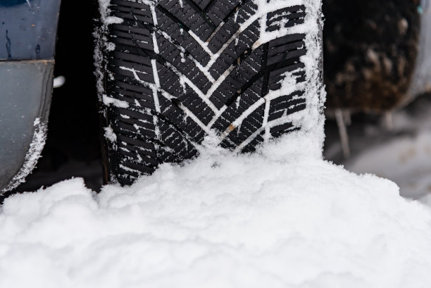 越野冬季轮胎塞满了厚厚的积雪。冬天被雪覆盖的道路上汽车轮胎的细节。冬天路上的汽车轮胎被雪覆盖。车辆在下雪的早晨。图片下载