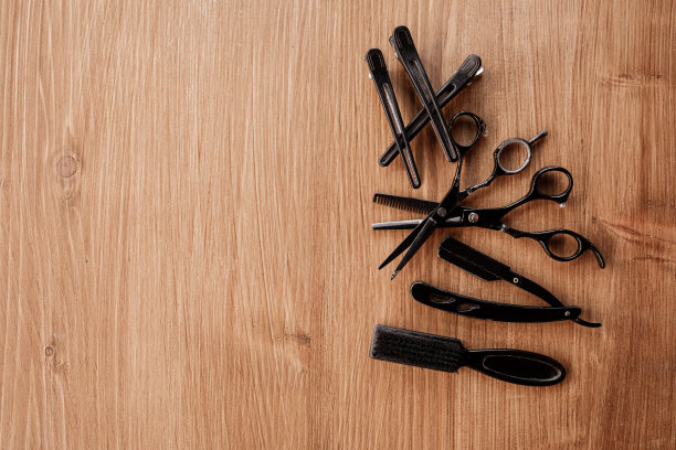 理发店的设备在木制背景与地方的文字。用梳子，剪刀，剃须用的老式剃须刀，黑色衣夹。专业美容工具。图片下载