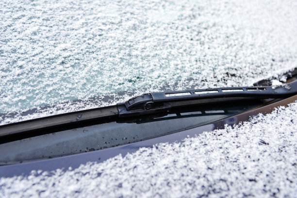 雪覆盖了部分汽车挡风玻璃。冬天，结冰的汽车挡风玻璃上覆盖着冰雪。关上车窗，前窗。图片下载