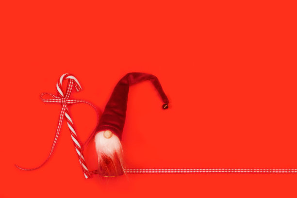 红白相间的拐杖糖和红色背景上的圣诞老人玩偶图片下载