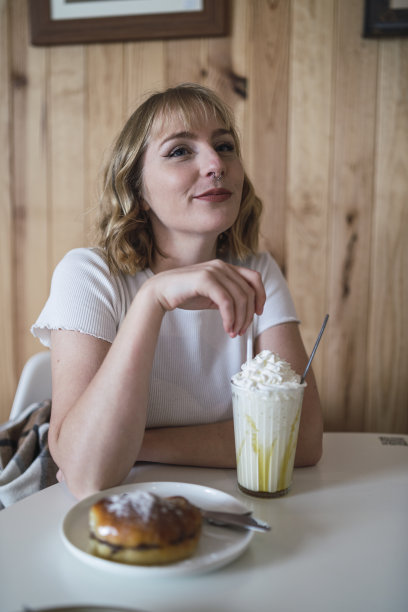 年轻的西班牙女子，一头金色短发，在餐厅里喝着甜饮料，吃着蛋糕图片下载