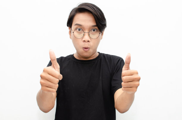 英俊迷人的亚洲男子快乐地微笑着，在白色背景下竖起大拇指以示赞美。图片下载