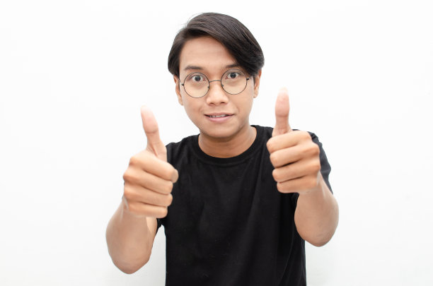 英俊迷人的亚洲男子快乐地微笑着，在白色背景下竖起大拇指以示赞美。图片下载